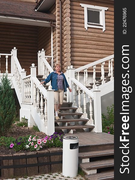 A woman stands on the steps of log cabin