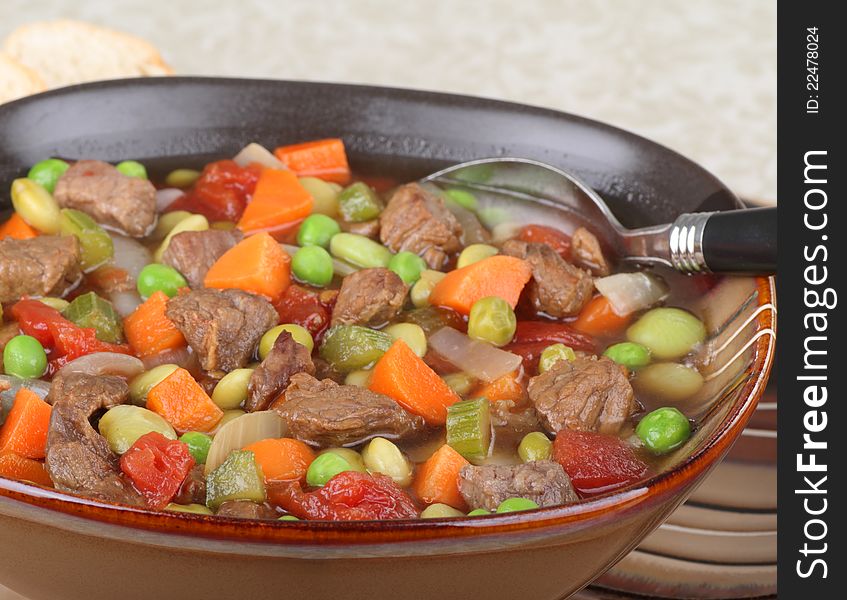 Closeup of a brown bowl of vegetable beef soup. Closeup of a brown bowl of vegetable beef soup