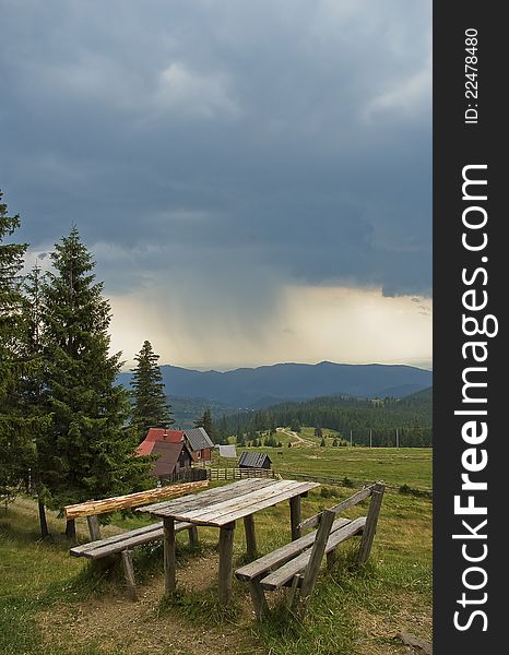 Stormy weather in the mountains in Transylvania with dark sky, wooden bench in front. Stormy weather in the mountains in Transylvania with dark sky, wooden bench in front.
