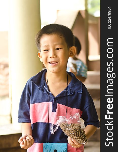 Asian boy holding fish food to feeding