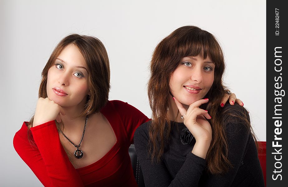 Portrait of young pretty sisters twins in studio on light background