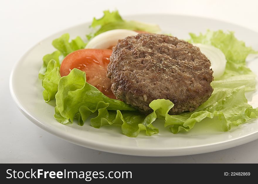 Meat rissole with lettuce, tomato and onion on the plate