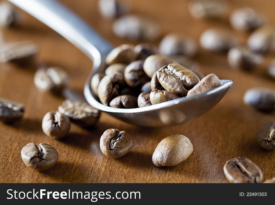 Close up photograph of a spoon full of coffee beans. Close up photograph of a spoon full of coffee beans