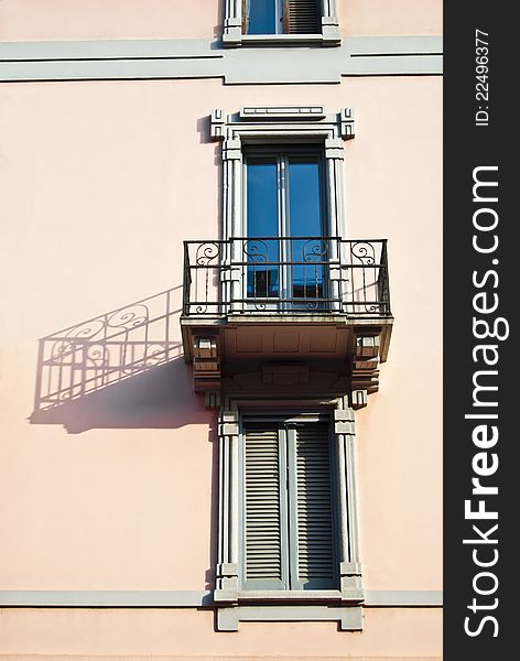 Old elegant balcony of a pink palace with lateral long and dramatic shadow