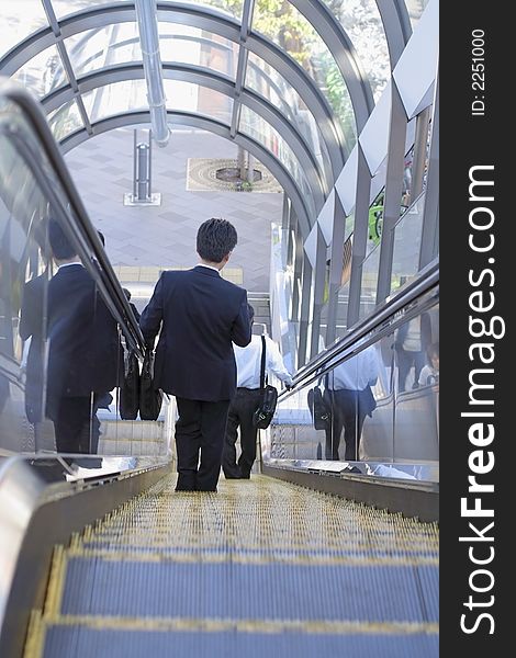 Businessman on a moving staircase in a big staircase.