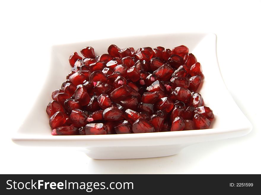 Handfull of  pomegranate grains in white squared bowl. Handfull of  pomegranate grains in white squared bowl