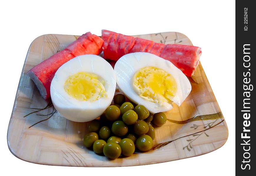 Egg, crab sticks and green peas on bamboo plate