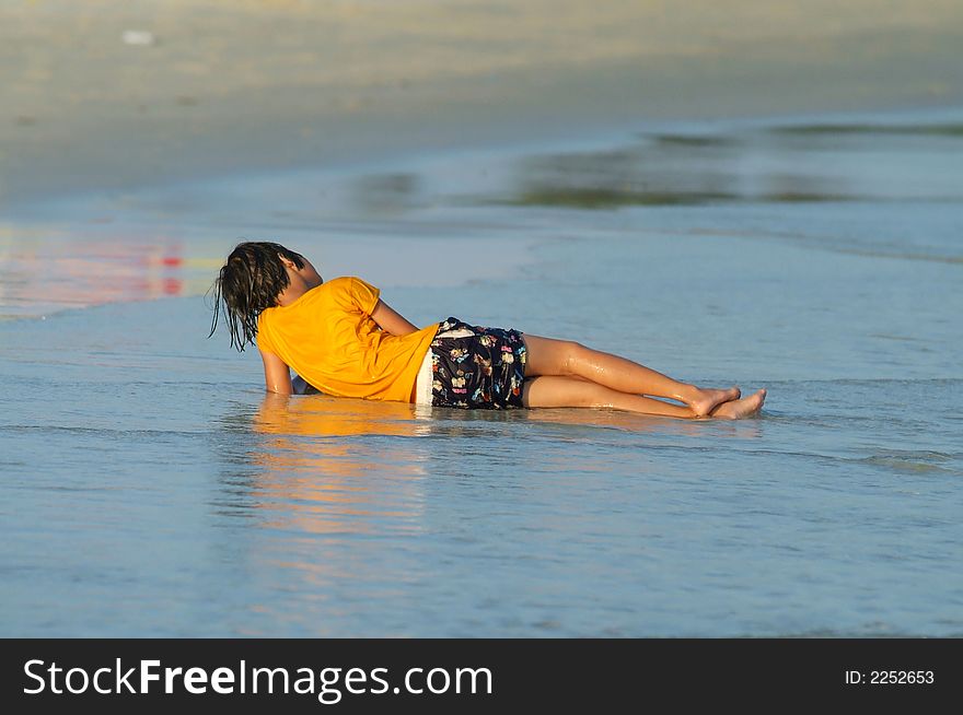 Wet girl in orange t-shirt resting on the beach. Shallow depth of field. Wet girl in orange t-shirt resting on the beach. Shallow depth of field.
