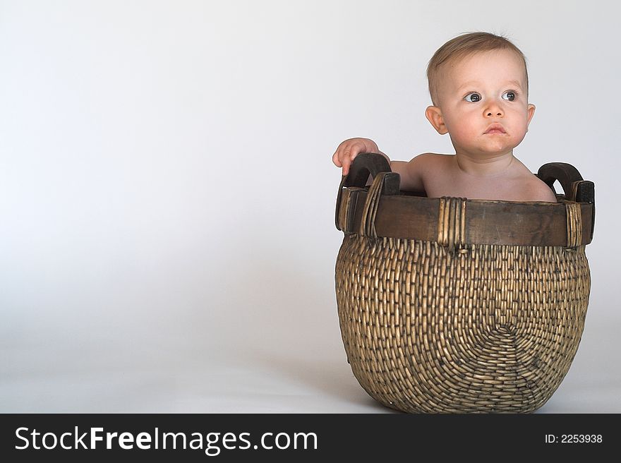 Image of cute baby sitting in a woven basket. Image of cute baby sitting in a woven basket