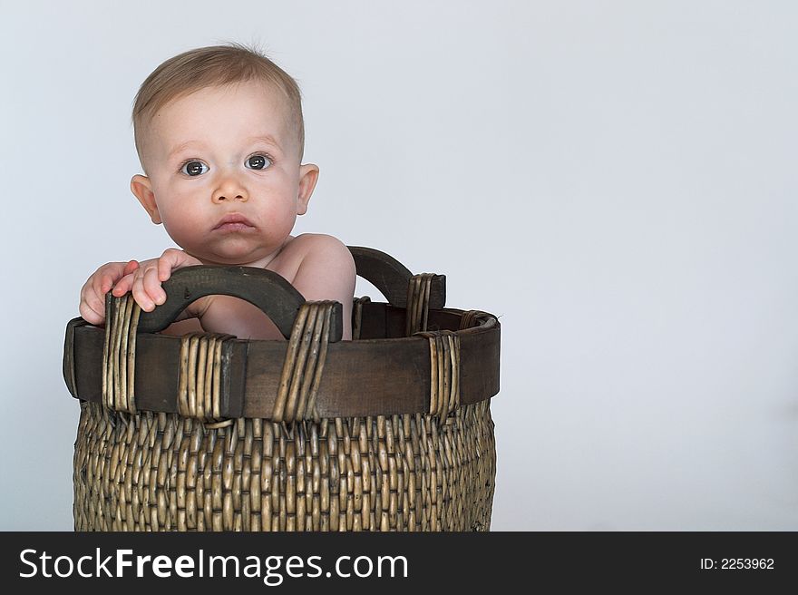 Image of cute baby sitting in a woven basket. Image of cute baby sitting in a woven basket