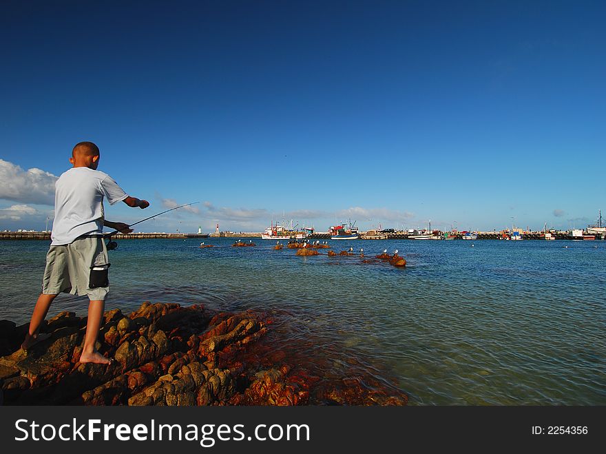 Boy fishing in Kalk Bay harbour near Cape Town. Boy fishing in Kalk Bay harbour near Cape Town