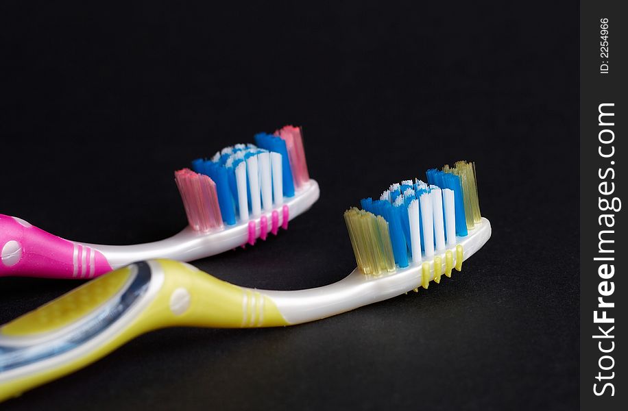 Yellow and pink toothbrush on black background