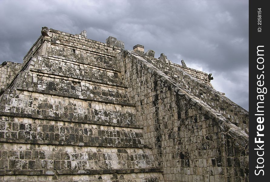 The close up of a pyramid with a cloudy background in Chichen Itza, Mexico.