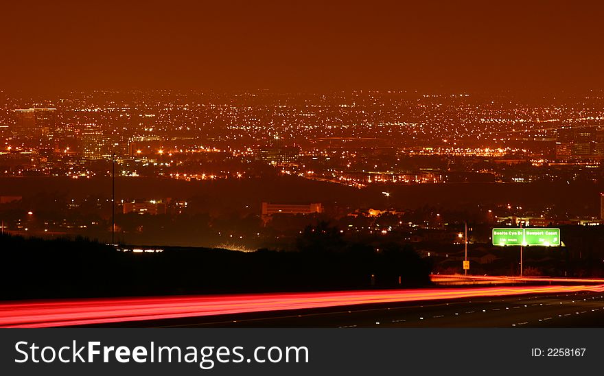 Night shot of a highway looking over a large city with a streak of passing cars. Night shot of a highway looking over a large city with a streak of passing cars