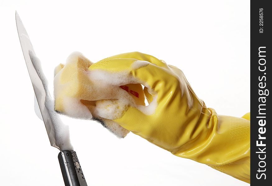 Hand in yellow rubber glove with yellow sponge and foam and knife. Hand in yellow rubber glove with yellow sponge and foam and knife