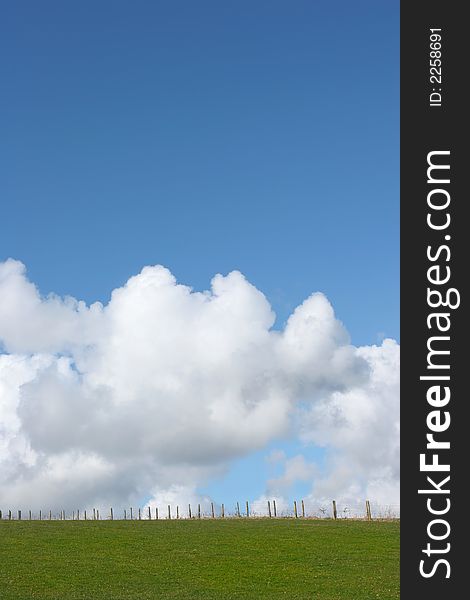 Wooden and wire fence in a field in rural countryside against a blue sky with cumulus clouds. Wooden and wire fence in a field in rural countryside against a blue sky with cumulus clouds.