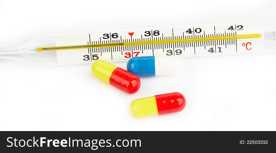 Colorful pills and pharmacy thermometer on white