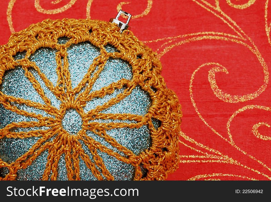 Close-up of a homemade ornament with a snowflake design. Set on a red background with gold glitter swirls. Focus is on the ornament. Close-up of a homemade ornament with a snowflake design. Set on a red background with gold glitter swirls. Focus is on the ornament.