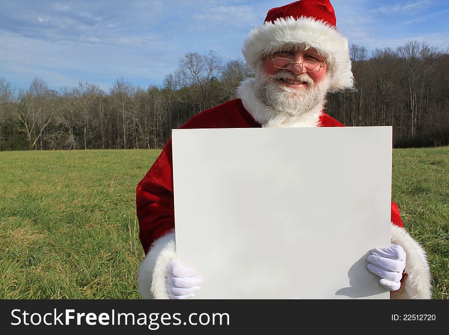 Santa Claus in an open field holding a large white sign.  Write your own message. Santa Claus in an open field holding a large white sign.  Write your own message.