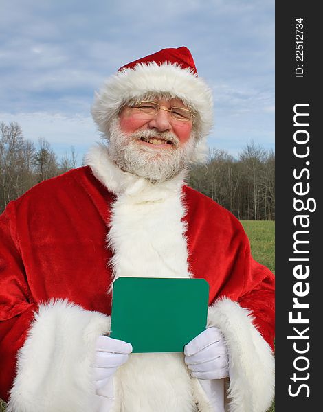 Santa Claus in an outdoor setting holding a chalk board in his gloved hands. Write your own message. Santa Claus in an outdoor setting holding a chalk board in his gloved hands. Write your own message.