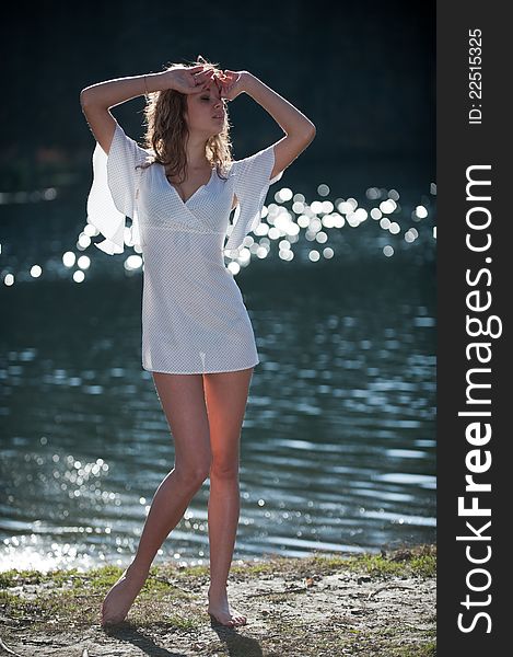 Portrait of young woman in a mini dress posing against the backdrop of water somewhere in the nature. Portrait of young woman in a mini dress posing against the backdrop of water somewhere in the nature