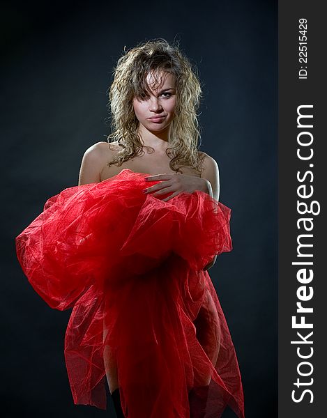 Portrait of naked pretty girl cover up in red nylon on a dark background in studio. Portrait of naked pretty girl cover up in red nylon on a dark background in studio
