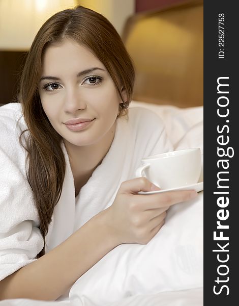 Portrait of beautiful brunette woman with cup on bed at bedroom. Portrait of beautiful brunette woman with cup on bed at bedroom