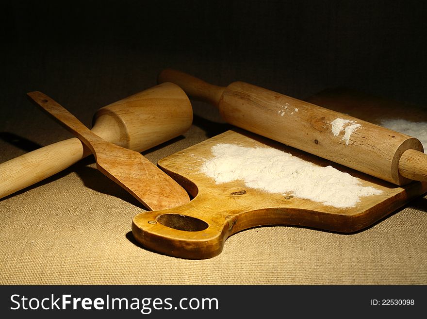 Set of wooden kitchen utensils and flour on canvas surface. Set of wooden kitchen utensils and flour on canvas surface