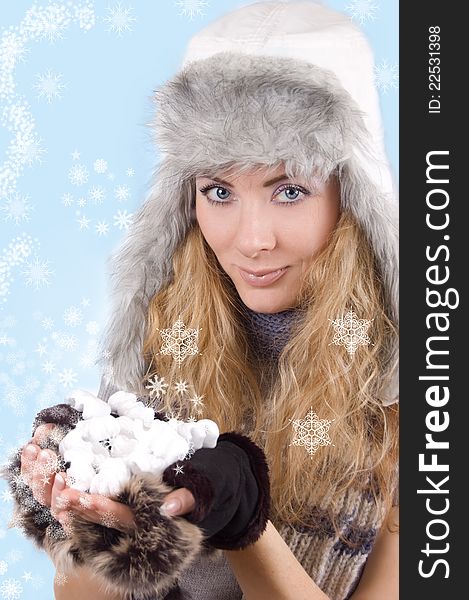 Woman in winter hat and gloves with snowflakes over blue back