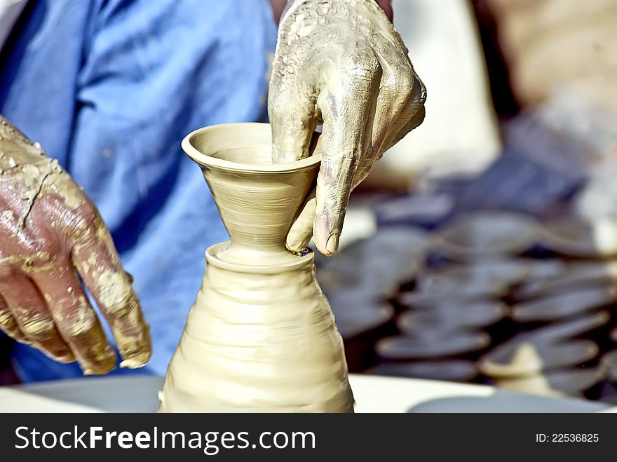 A clay goods manufacturer works on a thrower to make terracotta vases