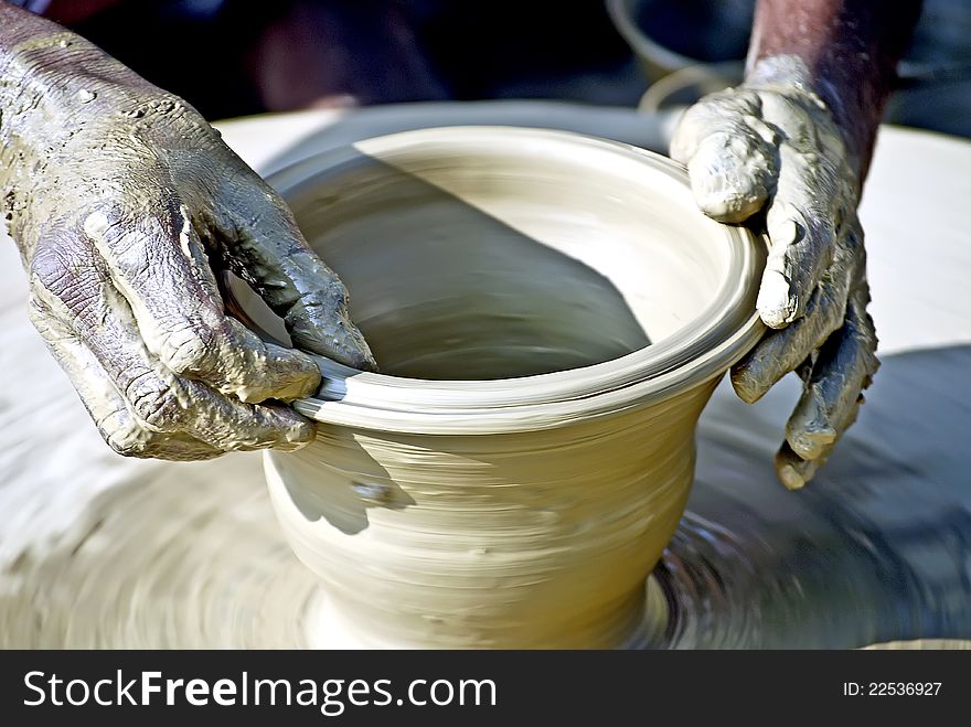 A clay goods manufacturer works on a thrower to make terracotta vases