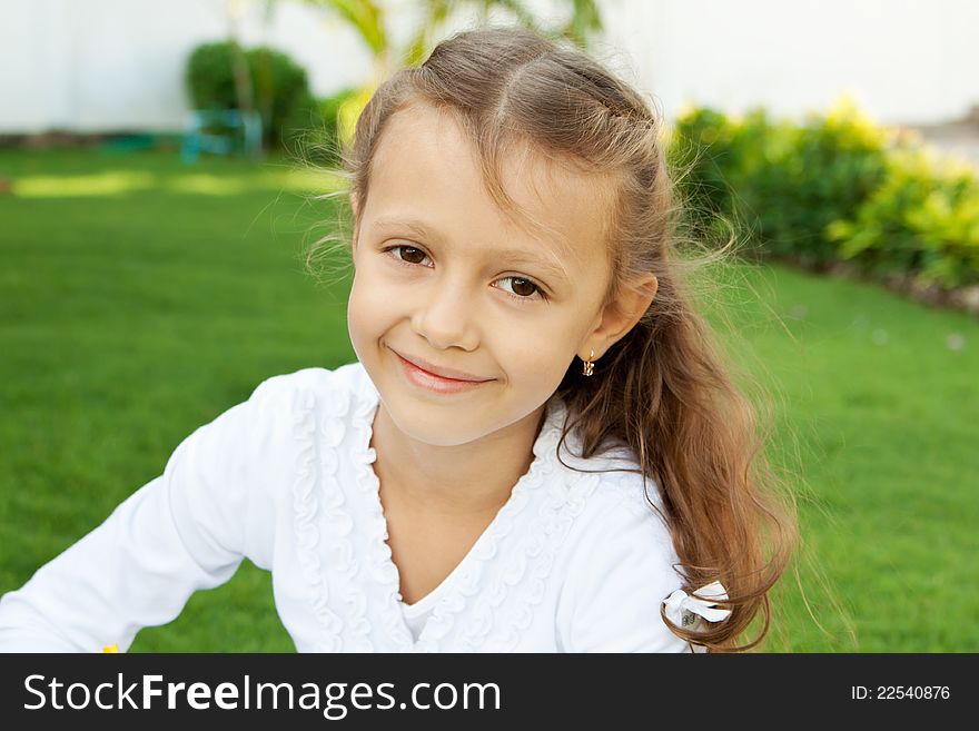 Little cute girl with long hair sitting on a green lawn. Little cute girl with long hair sitting on a green lawn