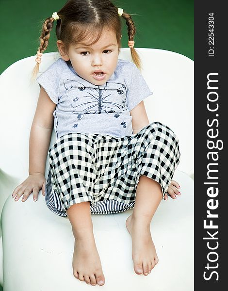 Cute little girl sitting on the white chair. Cute little girl sitting on the white chair