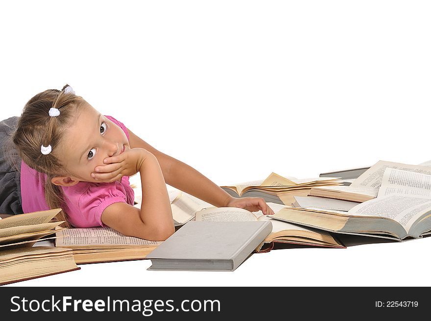 Nice little barefooted girl lying on the pile of open of books and smiling isolated on white background