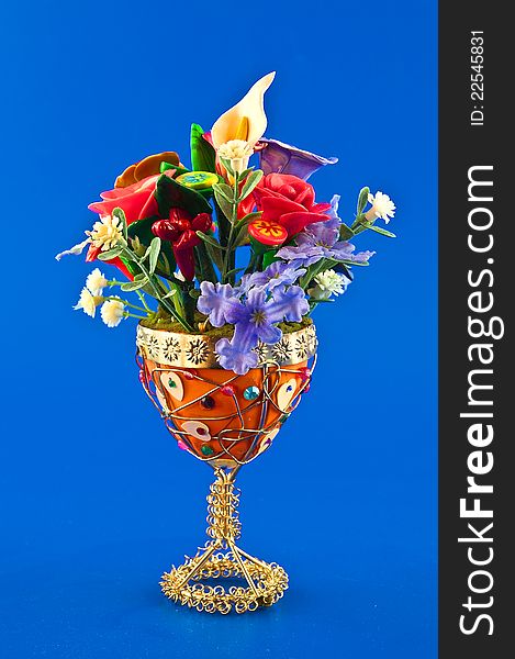 Decorative vase with artificial flowers against a blue background