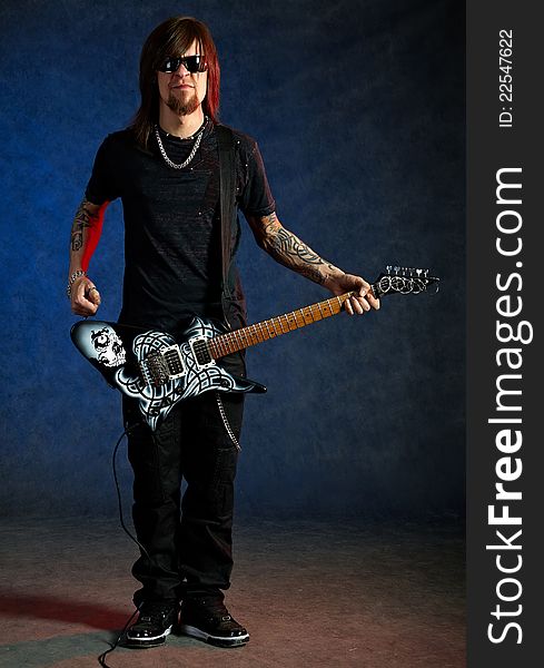 Brutal man with electric guitar on dark background
