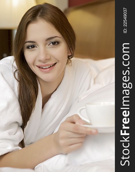 Portrait of beautiful brunette woman with cup on bed at bedroom. Portrait of beautiful brunette woman with cup on bed at bedroom
