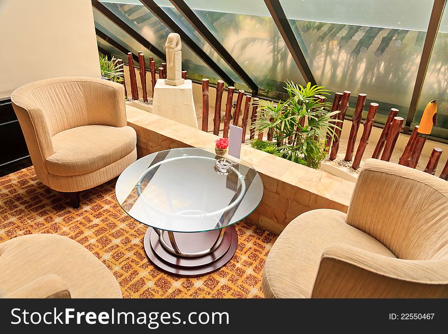 Armchairs and glass table inside a hotel Lobby.