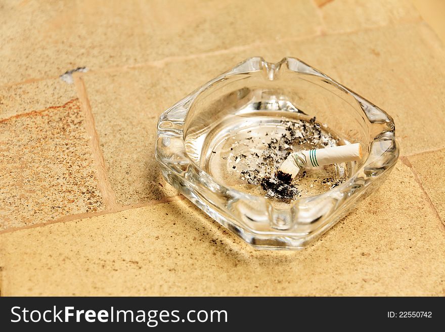 Cigarette butt in a glass ashtray. Cigarette butt in a glass ashtray.