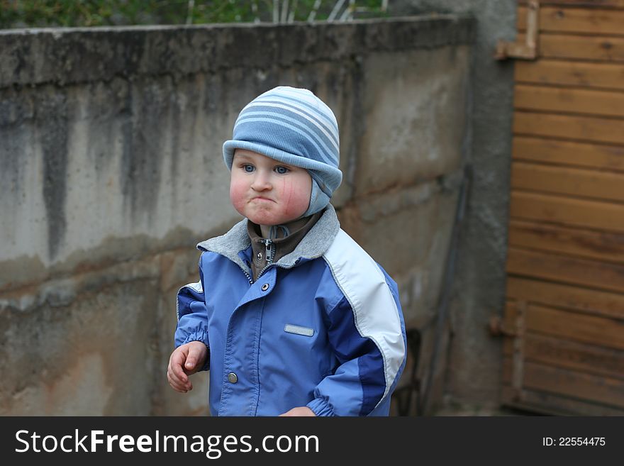 Dissatisfied children boy in autumn wear near garage on village demonstrate emotions. Dissatisfied children boy in autumn wear near garage on village demonstrate emotions