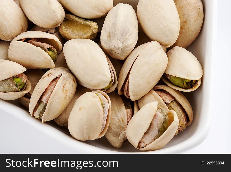 Close-up roasted and salted pistachios on white plate