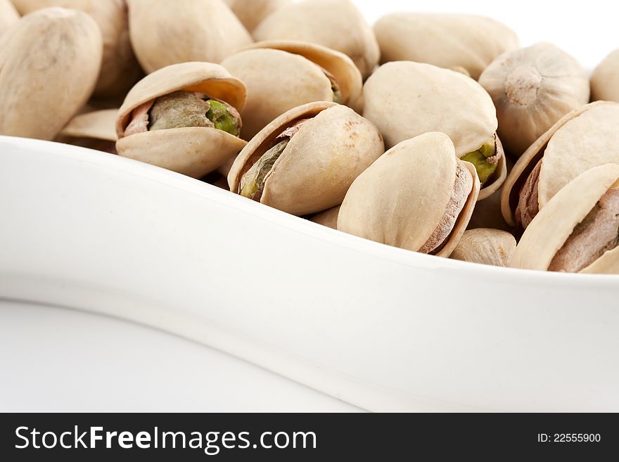 Close-up roasted and salted pistachios on white plate