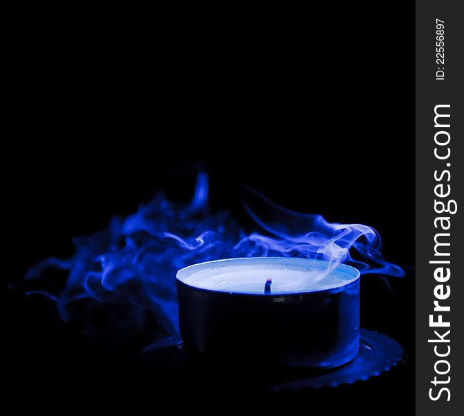 Extinguished candle with blue smoke on black background. Extinguished candle with blue smoke on black background