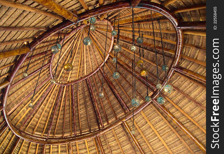 The indoor section of a palapa roof decorated with glass balls hanging on string.