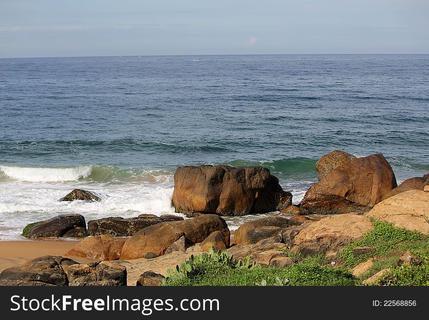 Scenic view of blue sky, sea and waves splashing on rocks at the beach, india. Scenic view of blue sky, sea and waves splashing on rocks at the beach, india