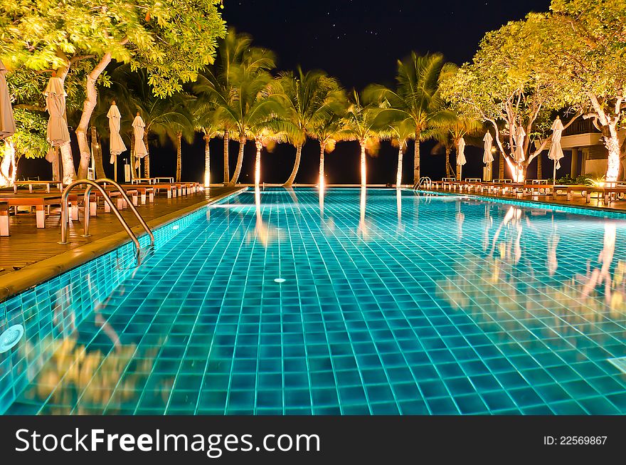 Night views of swiming pool among coconut tree