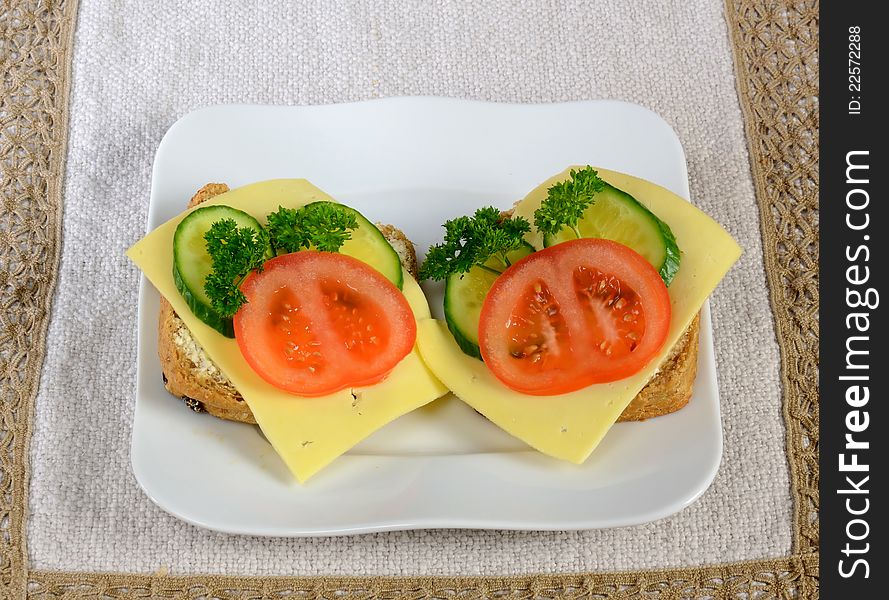 Devided bun sandwiches with cheese and vegetables on a plate. Devided bun sandwiches with cheese and vegetables on a plate