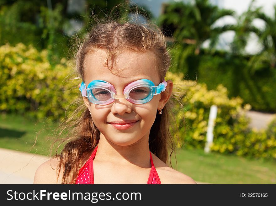 A beautiful girl with long hair in a red bathing suit wearing swimming glasses. A beautiful girl with long hair in a red bathing suit wearing swimming glasses