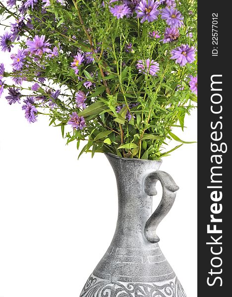 A bouquet of pink new york aster flowers in a jug against a white background. A bouquet of pink new york aster flowers in a jug against a white background