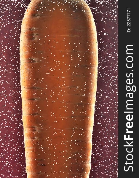 A carrot in the water with bubbles against a dark red background. A carrot in the water with bubbles against a dark red background